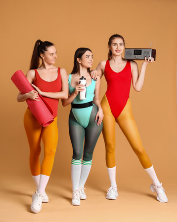 Sporty young women going to do aerobics on beige backgroundの写真素材