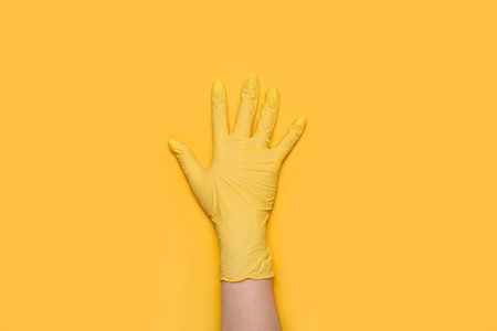 Woman in medical glove on yellow backgroundの写真素材