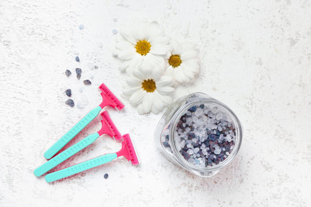 Safety razors, daisy flowers and jar with sea salt on white grunge backgroundの写真素材