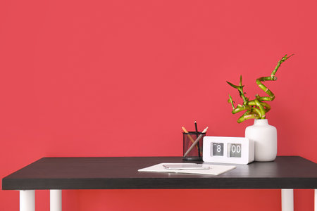 Workplace with stationery, mobile phone and clock near red wallの写真素材