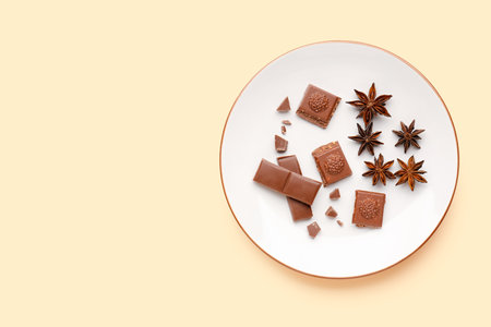 Plate with tasty chocolate and anise stars on color backgroundの写真素材
