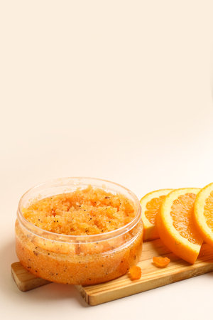 Wooden board with jar of natural body scrub and orange slices on light background, closeupの写真素材