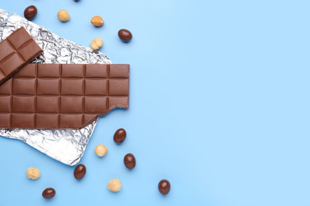 Foil with tasty chocolate, candies and hazelnuts on color backgroundの写真素材