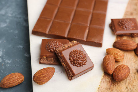 Board with tasty chocolate and almond nuts on table, closeupの写真素材