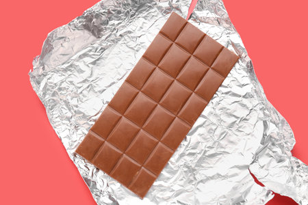 Foil with tasty chocolate bar on red background, closeupの写真素材