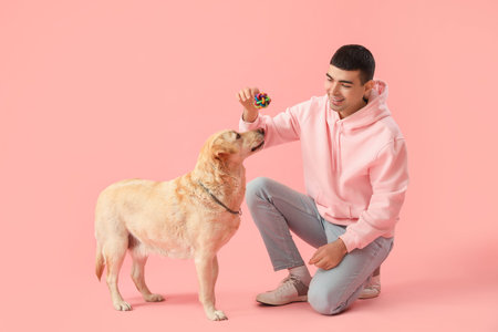 Young man with toy and cute Labrador dog on pink backgroundの写真素材