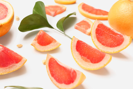 Composition with pieces of ripe grapefruit, seeds and plant leaves on white background, closeupの写真素材
