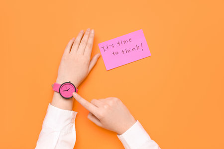 Woman pointing at wristwatch and paper with text IT'S TIME TO THINK on red backgroundの写真素材