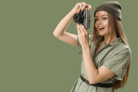 Fashionable young woman with vintage photo camera on green backgroundの写真素材