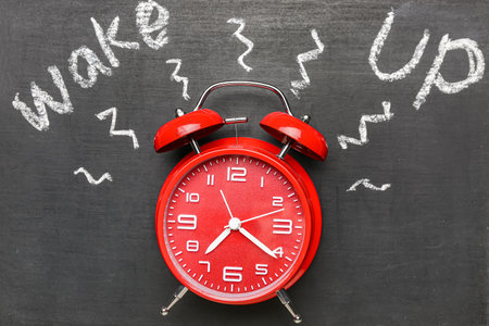 Alarm clock and text WAKE UP on chalkboard, closeupの写真素材