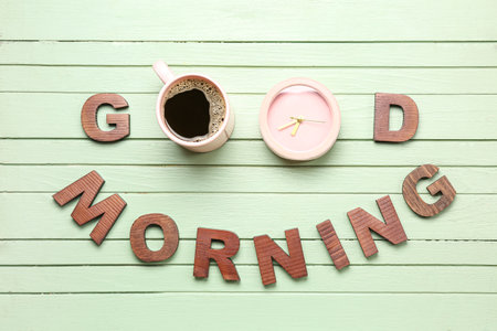 Text GOOD MORNING made of letters, cup with coffee and alarm clock on color wooden backgroundの写真素材