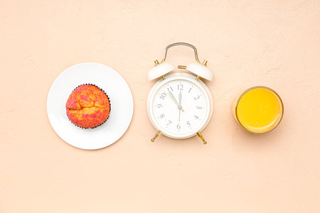 Tasty muffin,alarm clock and glass of juice on color backgroundの写真素材