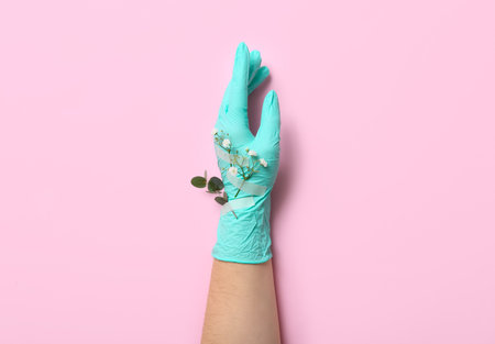 Woman in rubber glove with taped flowers on pink backgroundの写真素材