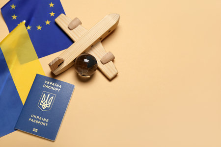 Passport, wooden airplane with flags of Ukraine and European Union on beige backgroundの写真素材
