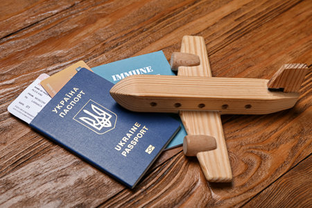 Ukrainian and immune passports with toy airplane on wooden background, closeupの写真素材