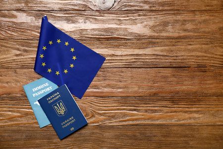 Ukrainian and immune passports with flag of European Union on wooden backgroundの写真素材