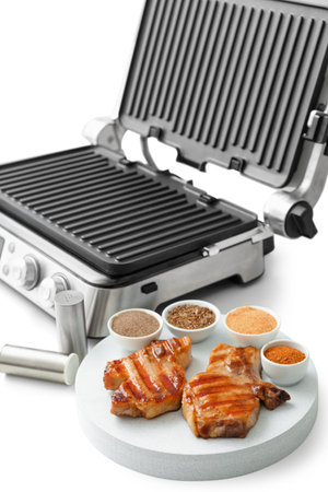 Modern electric grill, board with delicious steak and spices isolated on white backgroundの写真素材