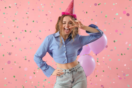 Happy young woman celebrating Birthday on pink backgroundの写真素材