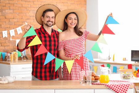 Young couple with flags celebrating Festa Junina (June Festival) in kitchen