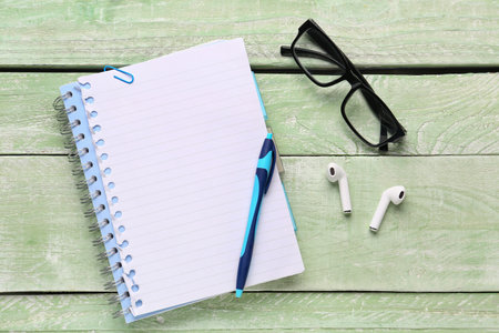 Composition with notepad, eyeglasses and earphones on green wooden backgroundの写真素材