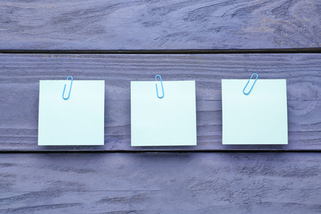 Sticky notes with paper clips on blue wooden backgroundの写真素材
