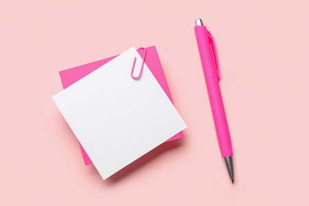 Sticky notes with paper clip and pen on pink backgroundの写真素材