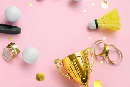 Frame made of gold cup with sports equipment on pink backgroundの写真素材