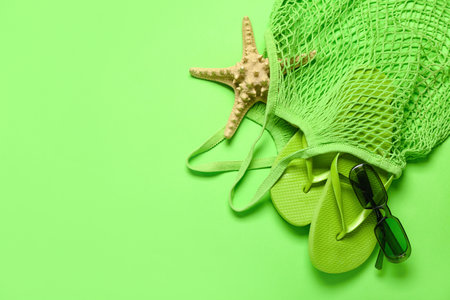 String bag with flip-flops, sunglasses and starfish on green backgroundの写真素材
