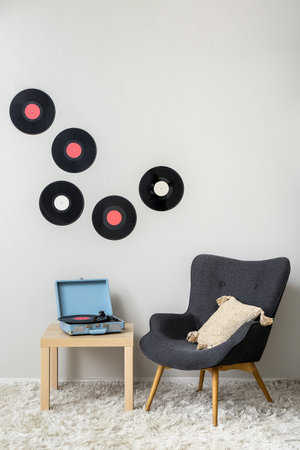 Record player with vinyl disk on table and armchair in living roomの写真素材