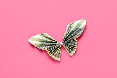 Origami butterfly made of dollar banknotes on pink backgroundの写真素材