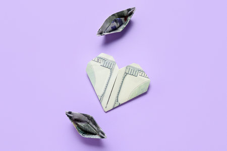 Origami boats and heart made of dollar banknotes on lilac backgroundの写真素材