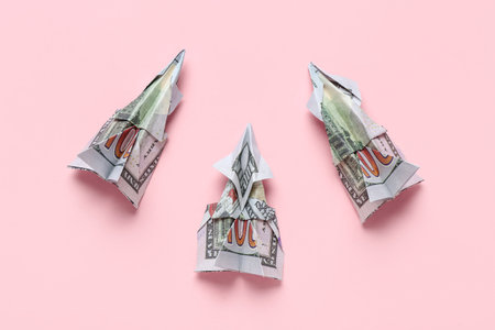 Origami airplanes made of dollar banknotes on pink backgroundの写真素材