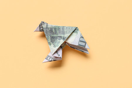 Origami bird made of dollar banknotes on beige backgroundの写真素材