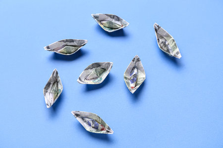 Origami boats made of dollar banknotes on blue backgroundの写真素材