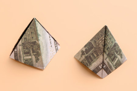 Origami pyramids made of dollar banknotes on beige backgroundの写真素材