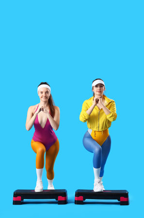 Sporty young women with steppers doing aerobics on blue backgroundの写真素材