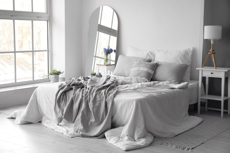Interior of light bedroom with mirror and spring flowers in vaseの写真素材