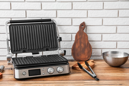 Modern electric grill on table near white brick wallの写真素材