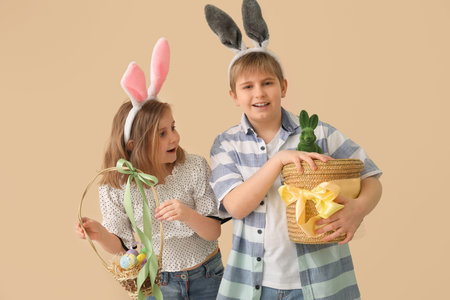 Little children in bunny ears with baskets of Easter eggs on beige background