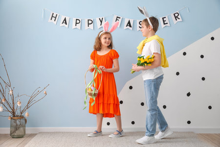 Little children in bunny ears with Easter eggs and tulips at home
