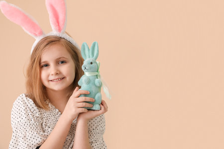 Little girl in bunny ears with Easter rabbit on beige backgroundの写真素材