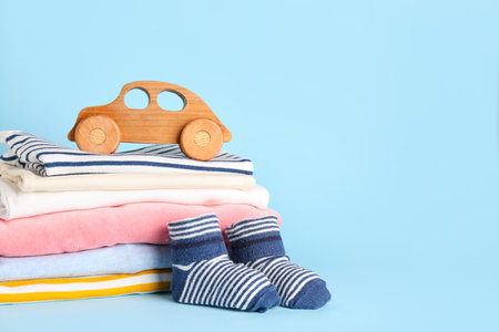 Stack of baby clothes, socks and wooden toy on color backgroundの写真素材