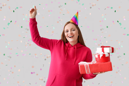 Beautiful woman with gifts celebrating Birthday on gray backgroundの写真素材
