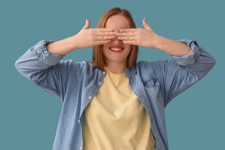 Beautiful redhead woman closing eyes with hands on blue backgroundの写真素材
