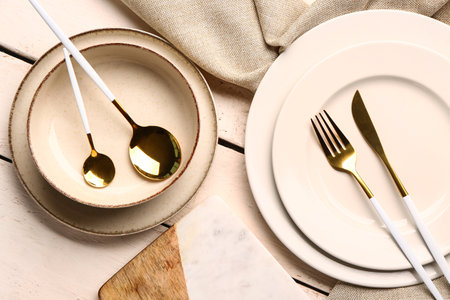 Board, dishes and set of cutlery on white wooden backgroundの写真素材