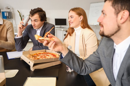 Group of business people eating tasty pizza in officeの写真素材