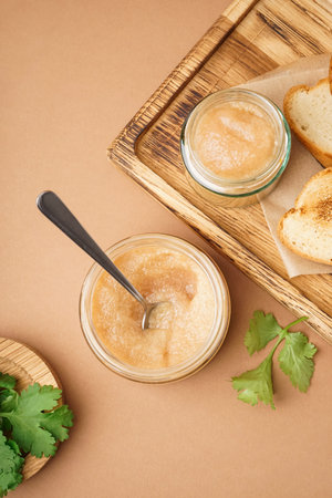 Jars with caviar of capelin and fried baguette on brown background