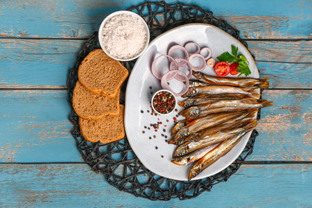 Plate with tasty smoked capelin and bread pieces on blue wooden backgroundの写真素材