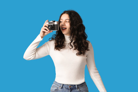 Teenage girl with photo camera on blue backgroundの写真素材