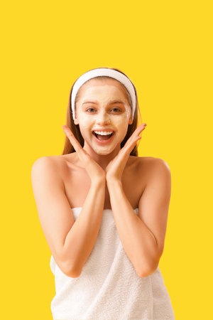 Happy young woman with applied turmeric mask on yellow backgroundの写真素材